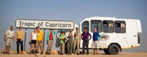 Kleinbus und Reisegruppe am südlichen Wendekreis in Namibia 