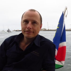 Porträt Sven Eltzschig - Gründer & Inhaber Namibia Favorites auf einem Katamaran in Walvis Bay mit namibischer Flagge