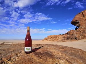 Rosé-Weinflasche aus dem Baselbiet von Tschäpperli-Weine am Mirabib-Felsen Namibias mit Aussicht über die Namib Richtung Küste