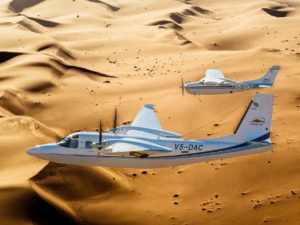 Zwei Flugzeuge - Aero Commander & Cessna 210 gemeinsam vor dem Hintergrund der Dünenlandschaft des Sossusvlei