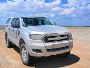 durch die unbefestigten Straßen schlammverkrusteter Ford Ranger inmitten der Etosha-Pfanne