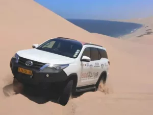 Toyota Fortuner in den Dünen der Namib mit Atlantik im Hintergrund