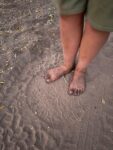 Foto von oben - Kinderfüsse in dem Fuss-Abdruck eines Elefanten